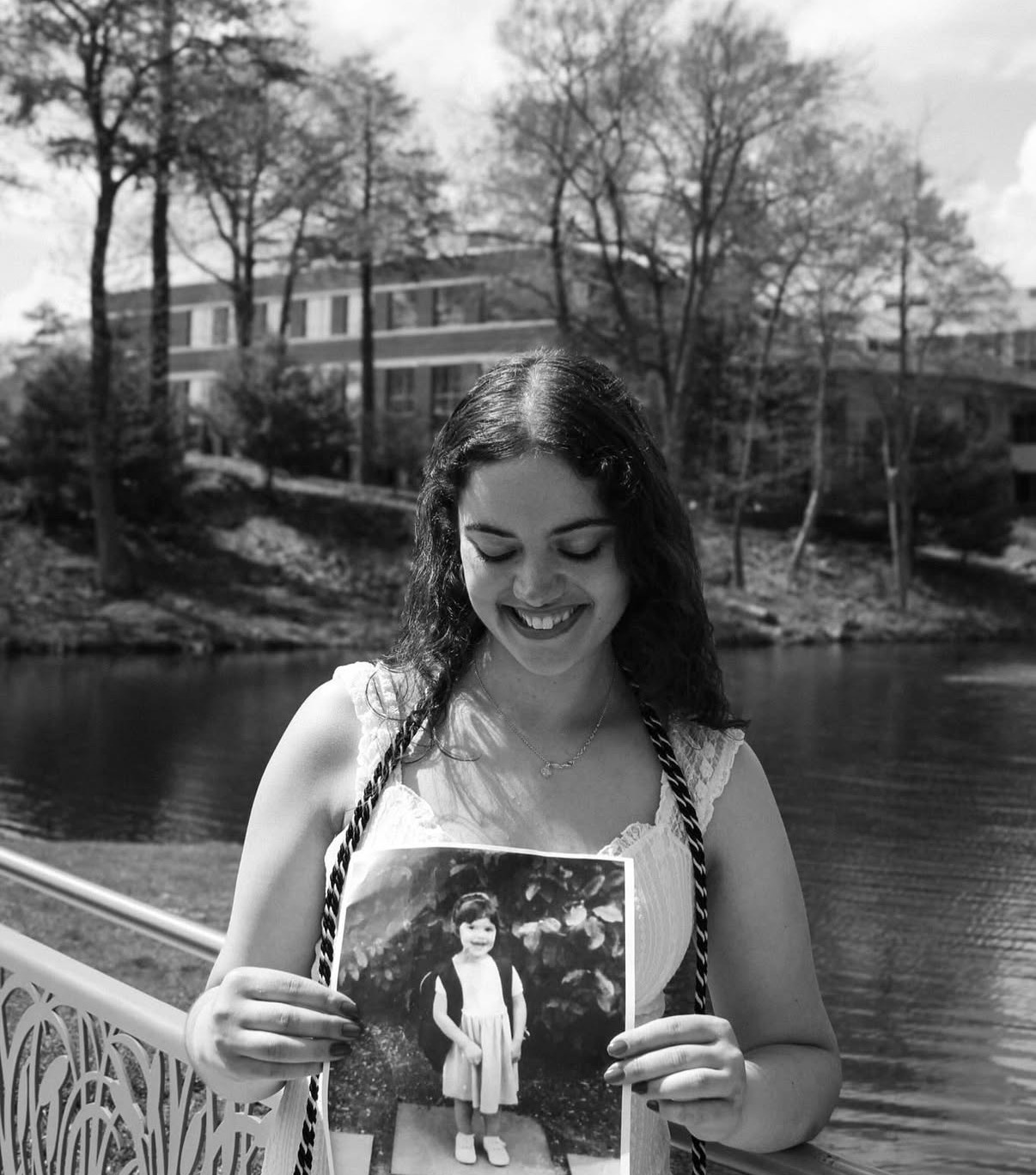 Black and white graduation portrait holding a childhood photo